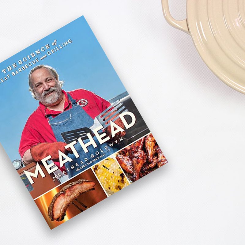 The cover of Meathead: The Science of Great Barbeque and Grilling beside a pot on a table.