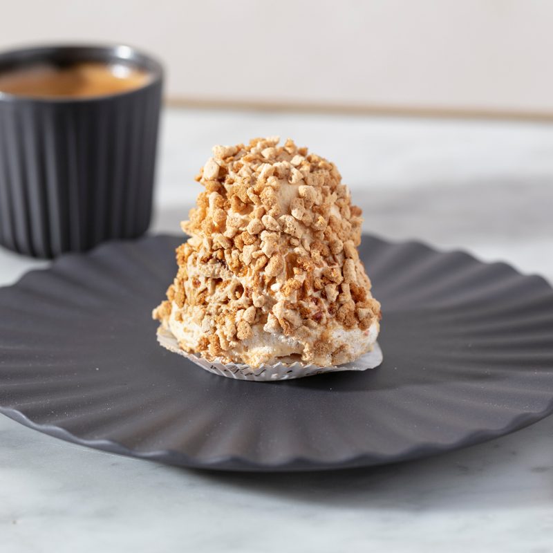 Merveilleux pastry on a plate next to a golden spoon.