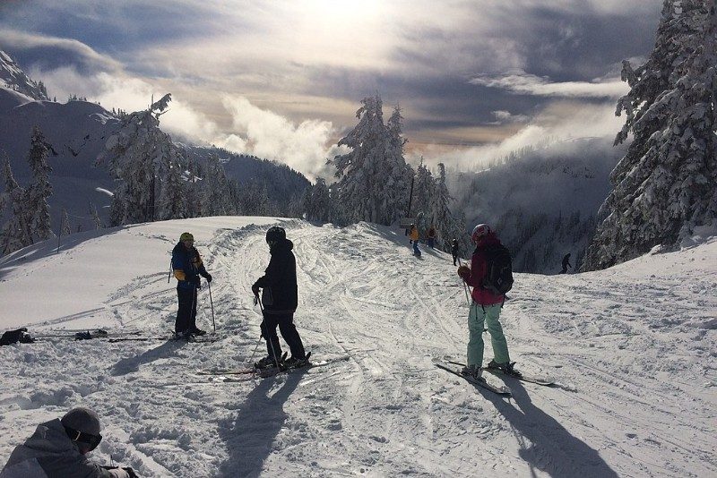 Three skiers on a flat spot atop a mountain
