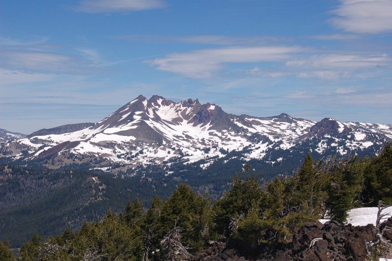 view of snow covered mountain with evergreen trees at the base.