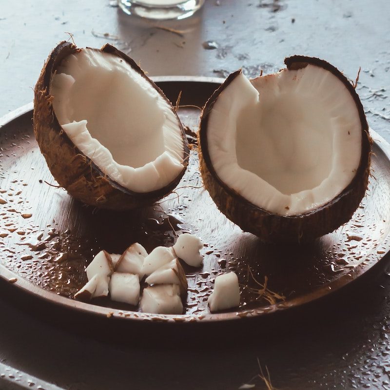 Cracked coconut served on a wooden plate.