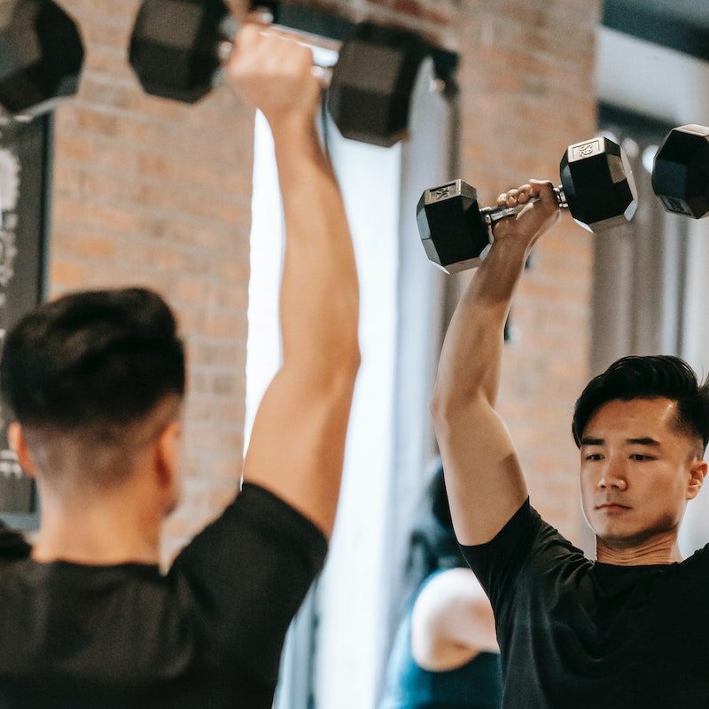 Man lifting weights by mirror