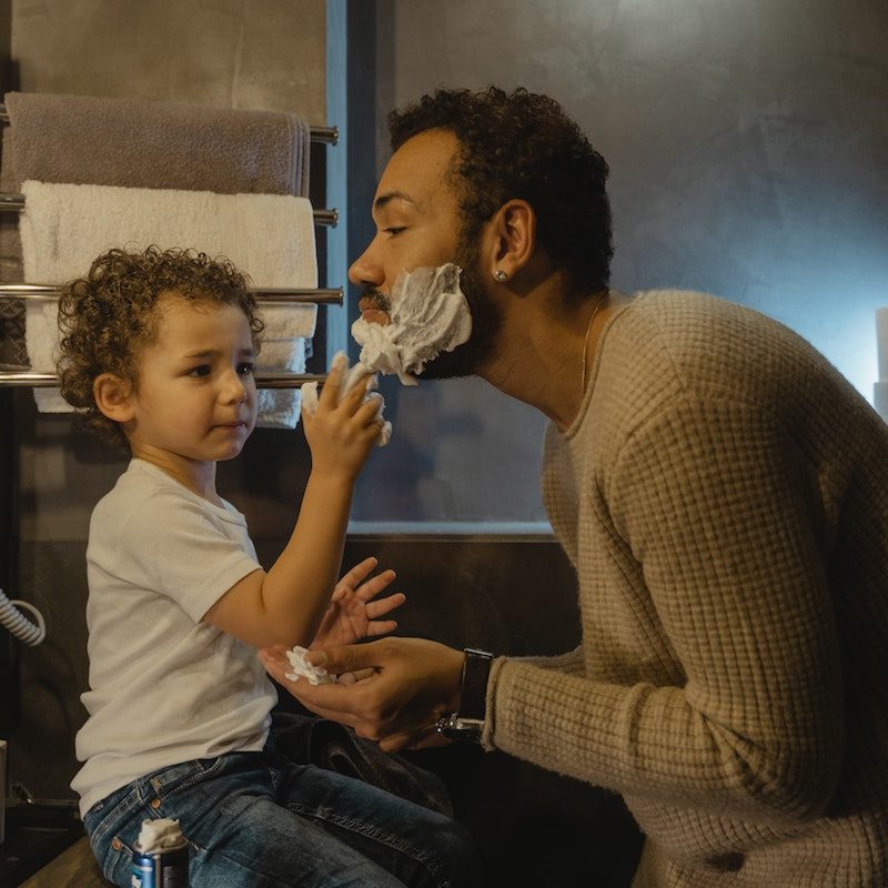 Child helping man shave.