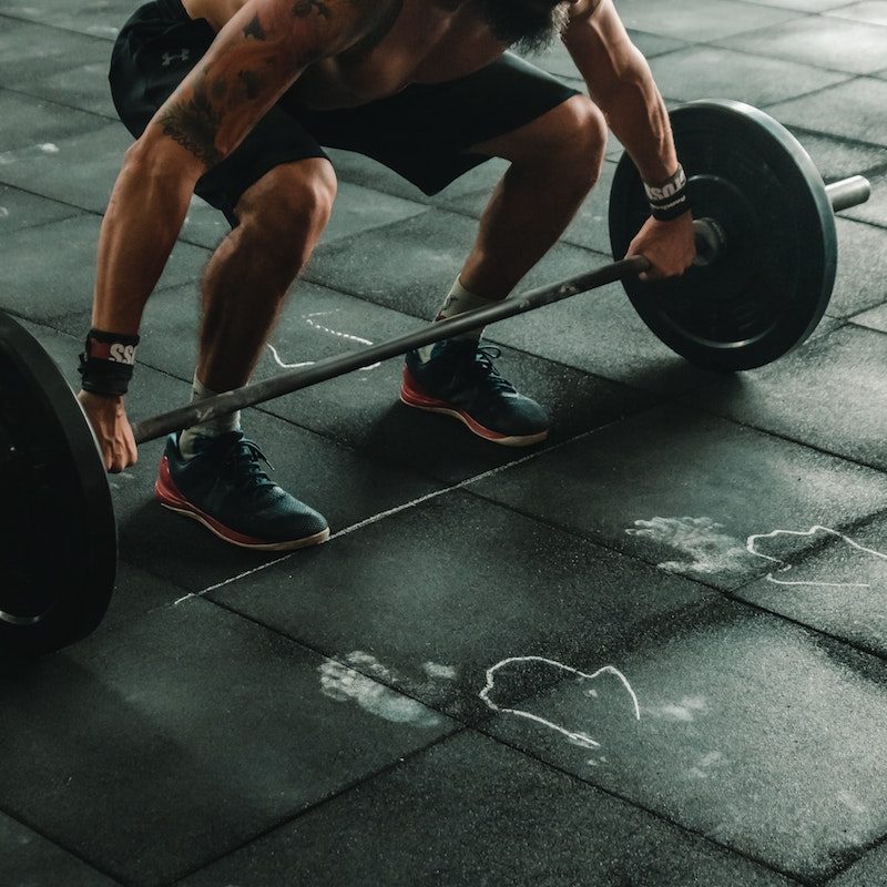 Man in a squatting position doing a deadlift