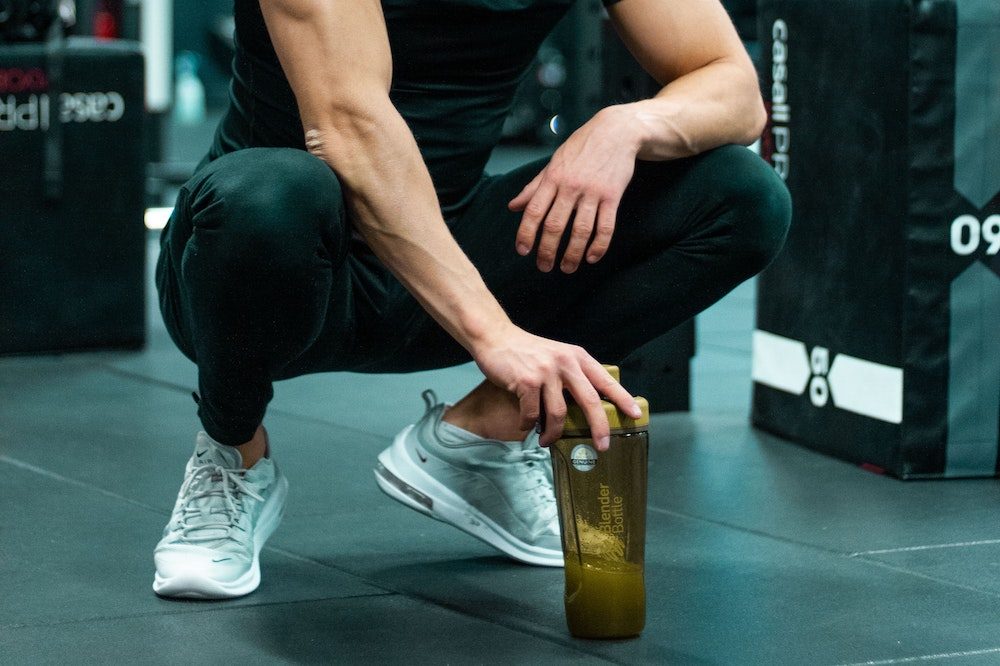 Man squatting down with pre-workout supplement