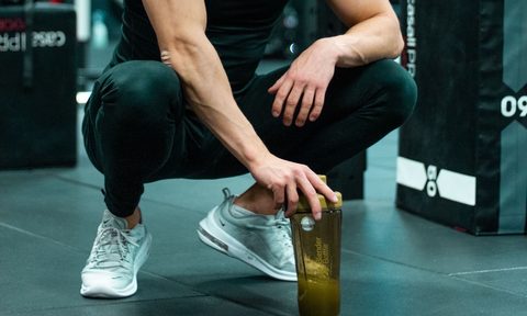 Man squatting down with pre-workout supplement