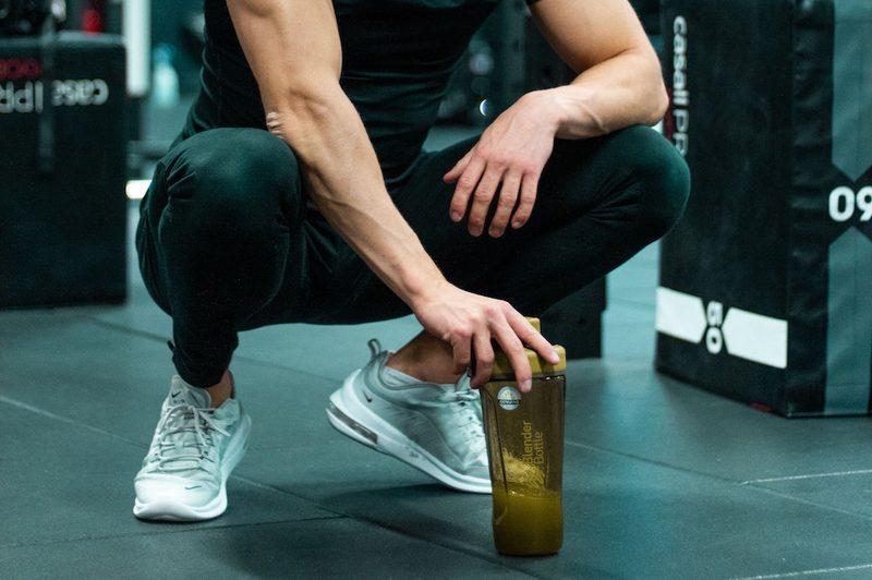 Man squatting down with pre-workout supplement