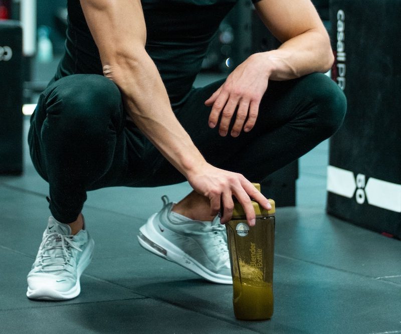 Man squatting down with pre-workout supplement