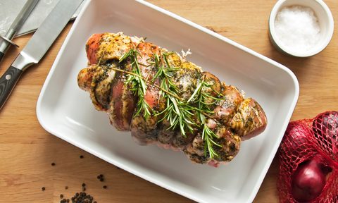 Roast lamb on a baking sheet with herbs.