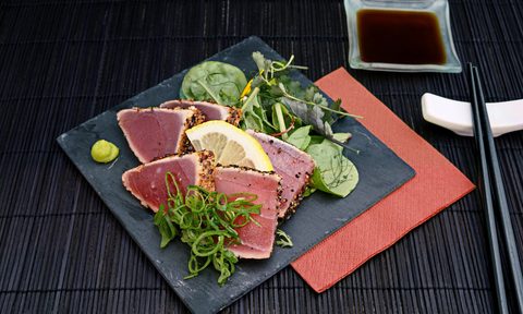 Tuna tataki with mixed green and soy sauce on a square plate.