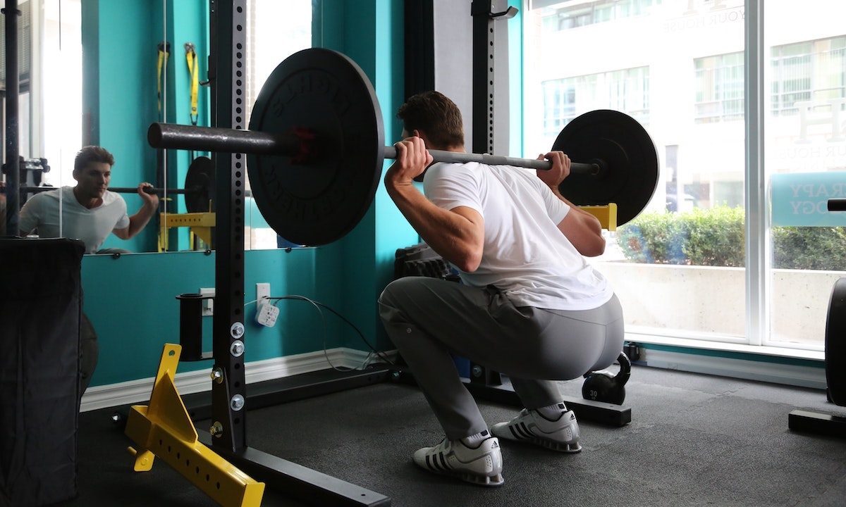 man doing heavy back squat for glutes.