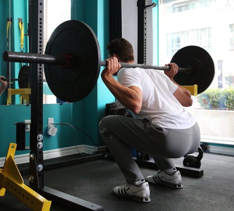 Man doing heavy back squat for glutes