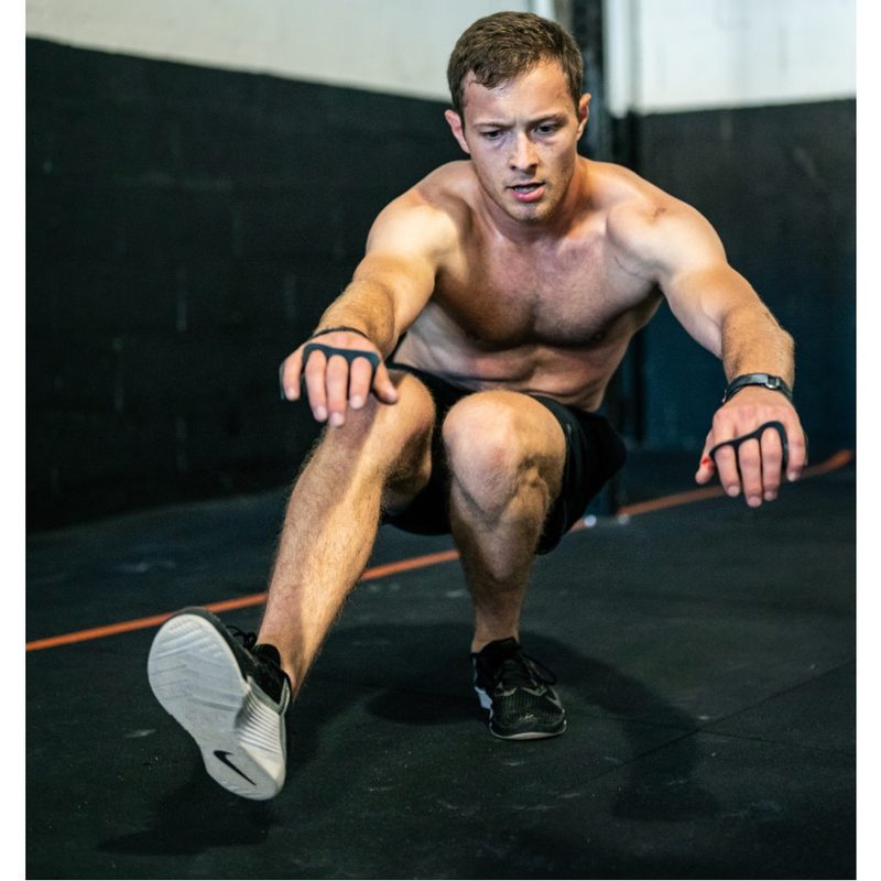 Shirtless man performing a pistol squat in a gym.