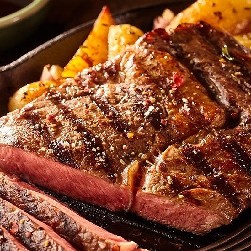 A close-up of a sliced grilled meat on a plate.