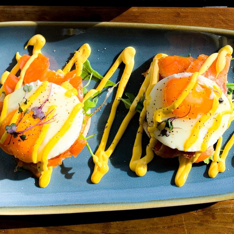 Two fried eggs and salmon served on a blue oval plate.