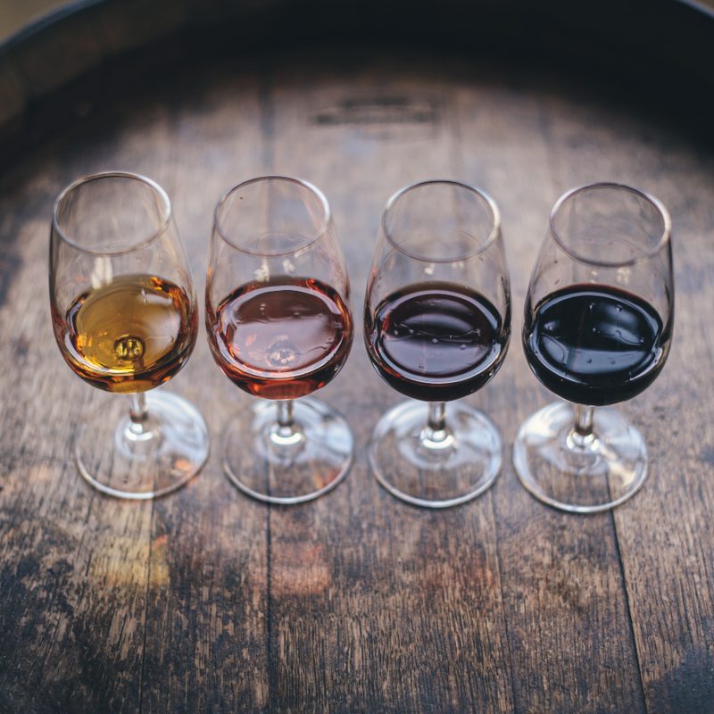 Four wine glasses on top of an oak barrel.