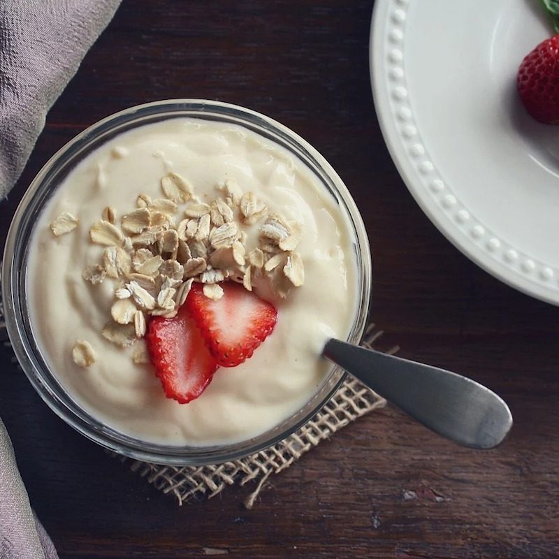 Bowl of yogurt with oats and sliced strawberries.