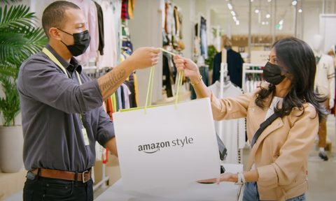 An Amazon Style clerk hands over a purchase to a customer.