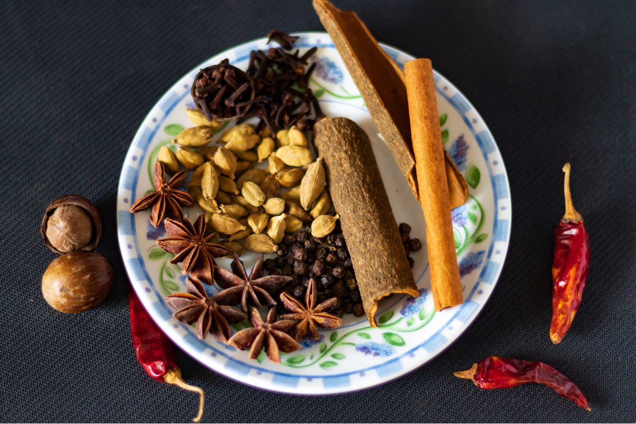 Variety of Indian masala chai spices - star anise, cloves and cinnamon on a plate.