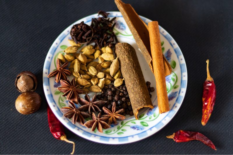 Variety of Indian masala chai spices - star anise, cloves and cinnamon on a plate.