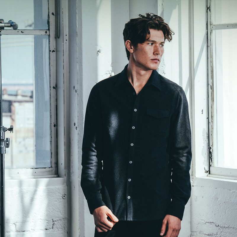 Man standing in loft space wearing Mission Workship's The Nash gray shirt-jacket.