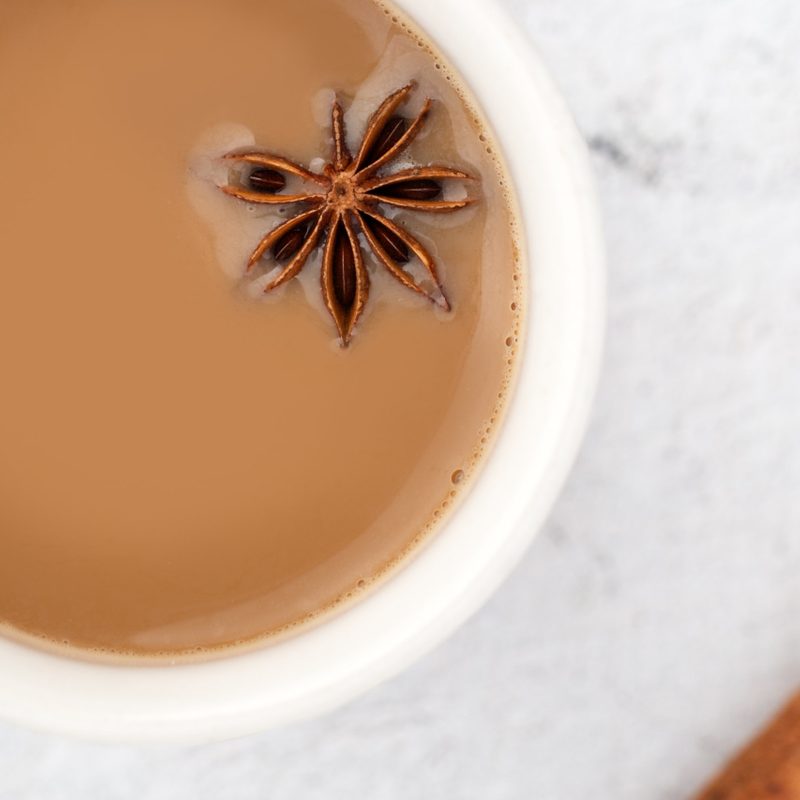 Indian chai in a white cup with floating star anise.