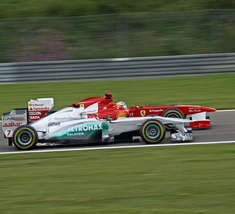 Two formula 1 race cars passing each other.