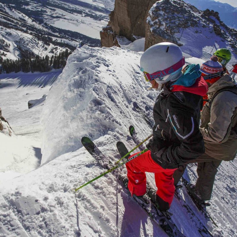 Skiiers look down couloir from the edge