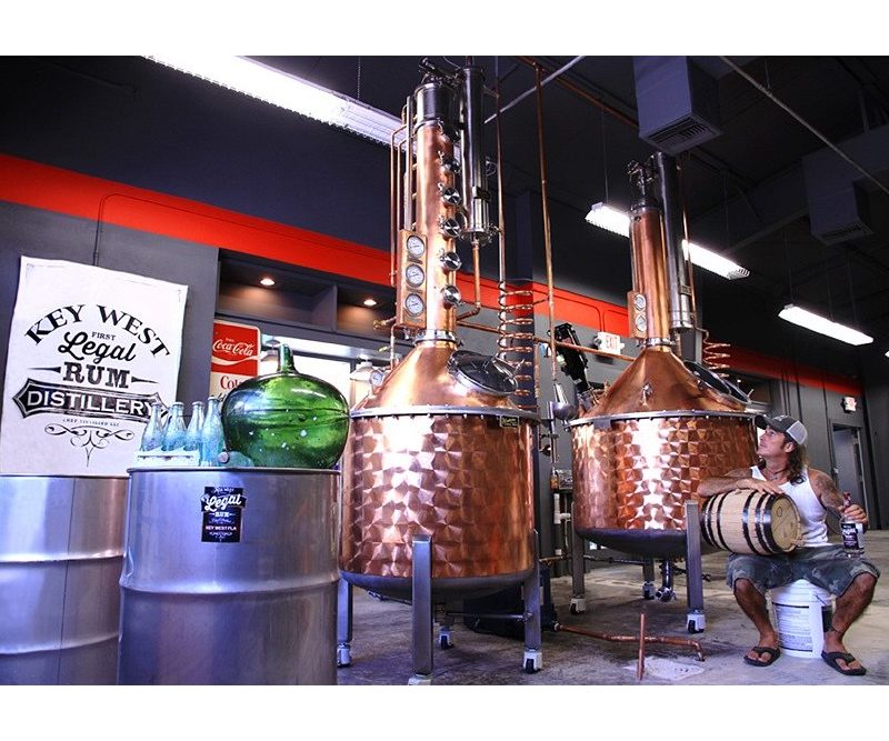 Distiller sits beside copper stills at Key West Legal Rum Distillery