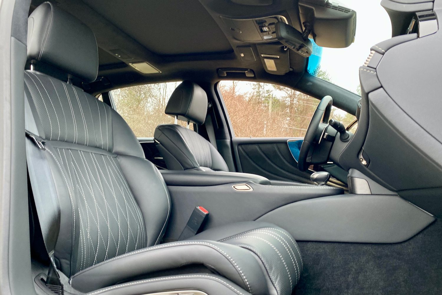 The front passenger seat in the 2021 Lexus LS500 from outside with trees in the back.