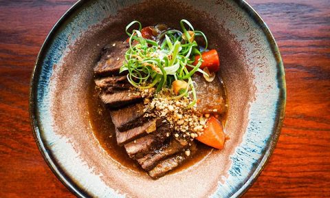 Overhead shot of Korean galbi-jjim short ribs from Perilla restaurant in Chicago, placed on wooden table.