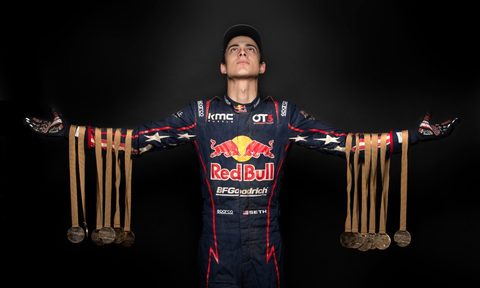Race driver Seth Quintero holds up his record-setting 1 stage winning medals from the 2022 Dakar Rally.