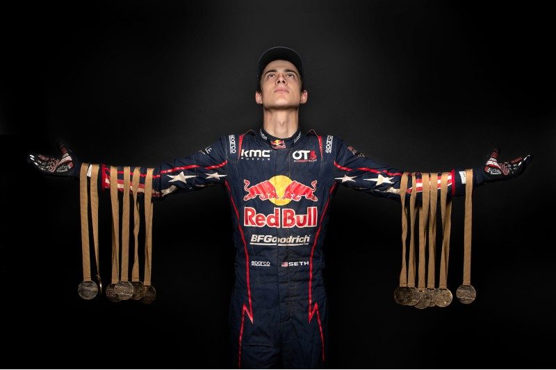 Race driver Seth Quintero holds up him record-setting 12 stage winning medals from the 2022 Dakar Rally.