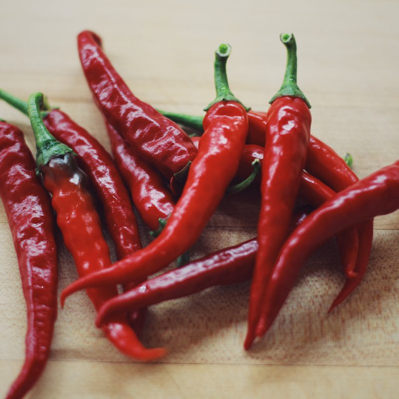 Handful of fresh red chili peppers on a wooden table.