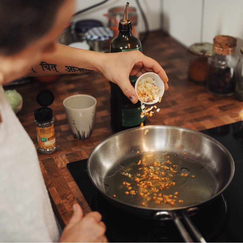 Woman adds garlic to pan of oil