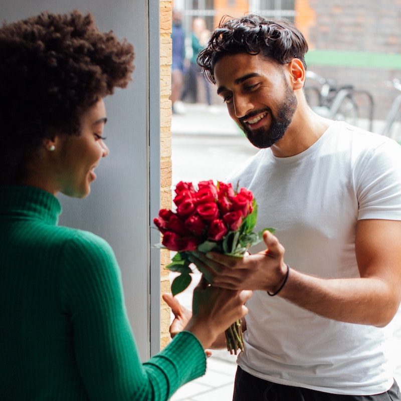 Man giving woman a bouquet or red roses.
