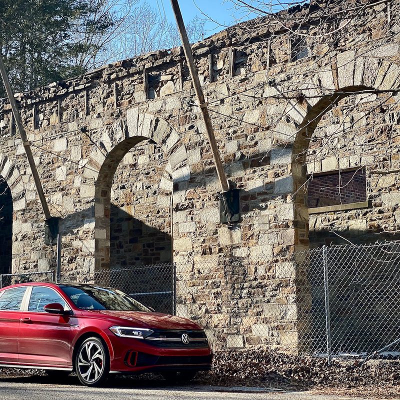 2022 Volkswagen Jetta side profile from the front in front of an abondoned building.