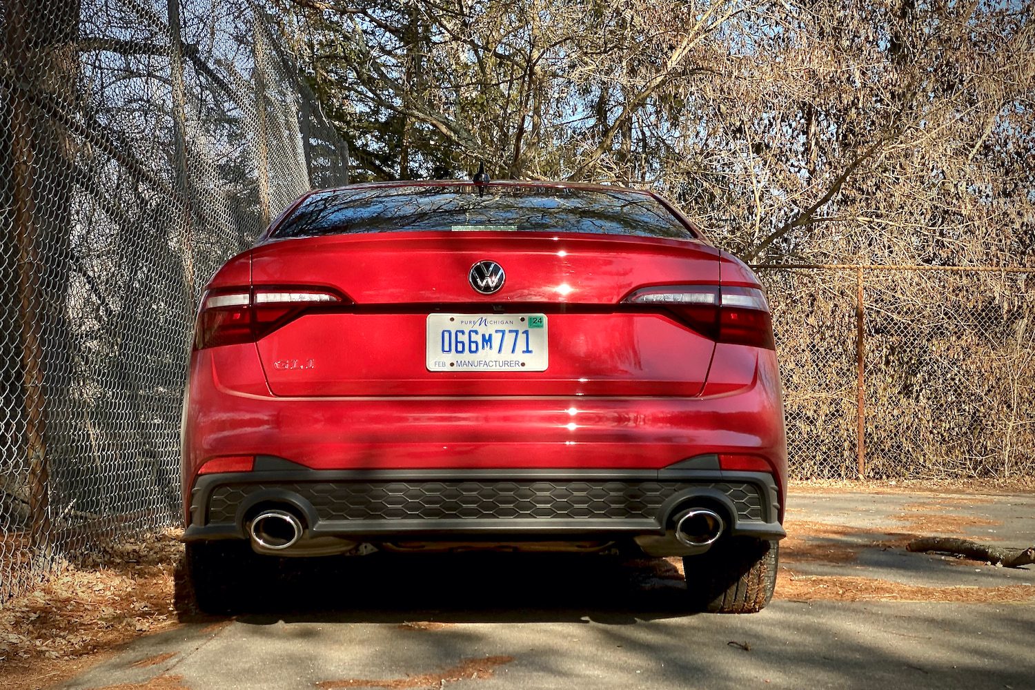 Close up of 2022 Volkswagen Jetta rear end on a concrete parking lot with trees in the background.