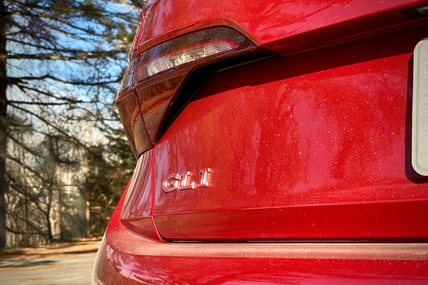 Close up of 2022 Volkswagen Jetta GLI rear badge with trees in the back.