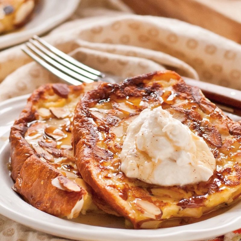 Two Almond French toast on white plate with fork.