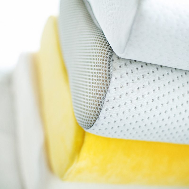 A close-up of a stack of memory foam pillows on a mattress.