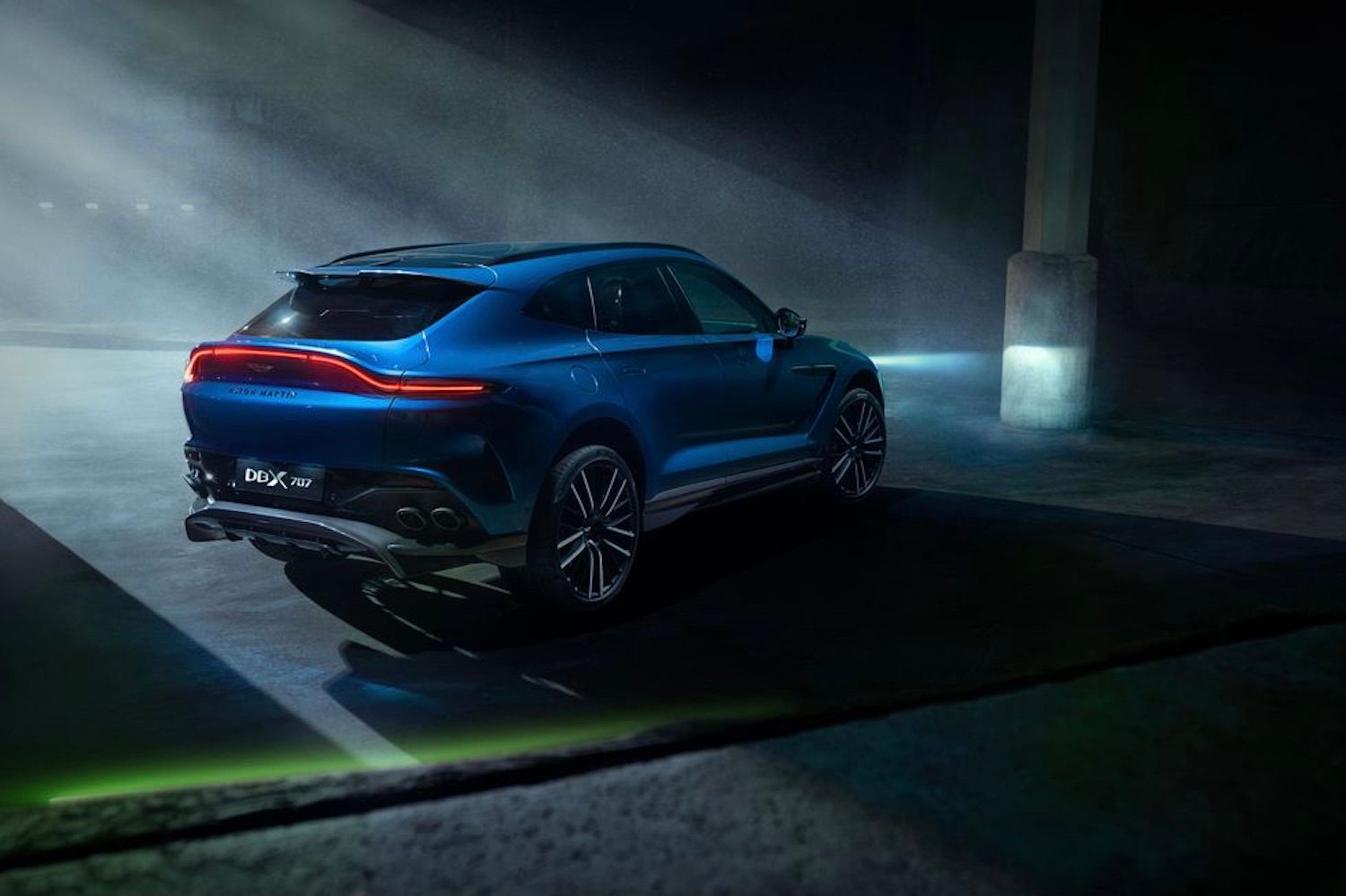 Aston Martin DBX 707 rear end from passenger's side in a dark warehouse.