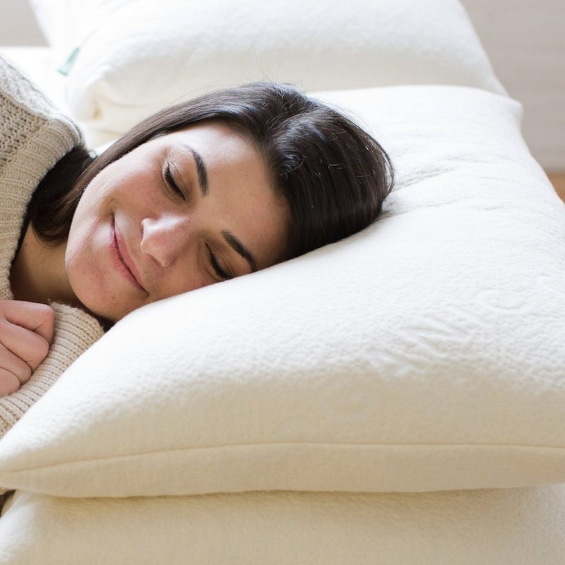 A woman rests her head on an Avocado Green pillow.