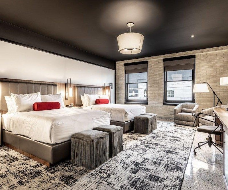 Bedroom view of Bottleworks Hotel featuring two beds and a one seater.