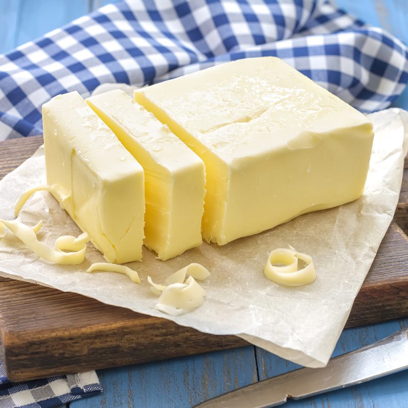 A sliced butter on paper on wooden cutting board.