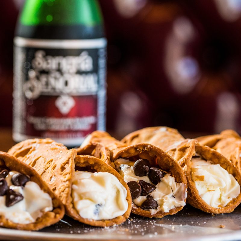 Cannolis on a metal serving tray.