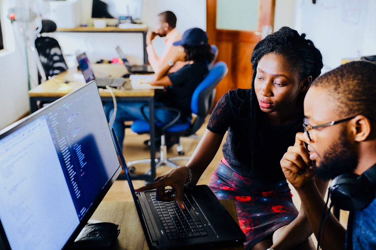 Two people studying a computer in a classroom.
