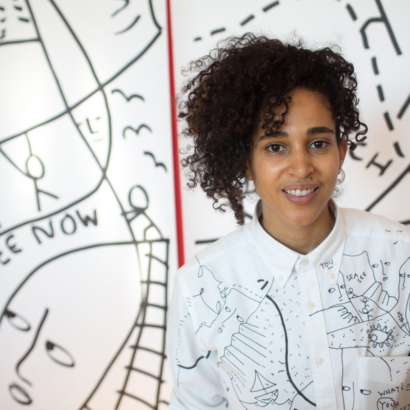 Shantell Martin posing with her art in the background.