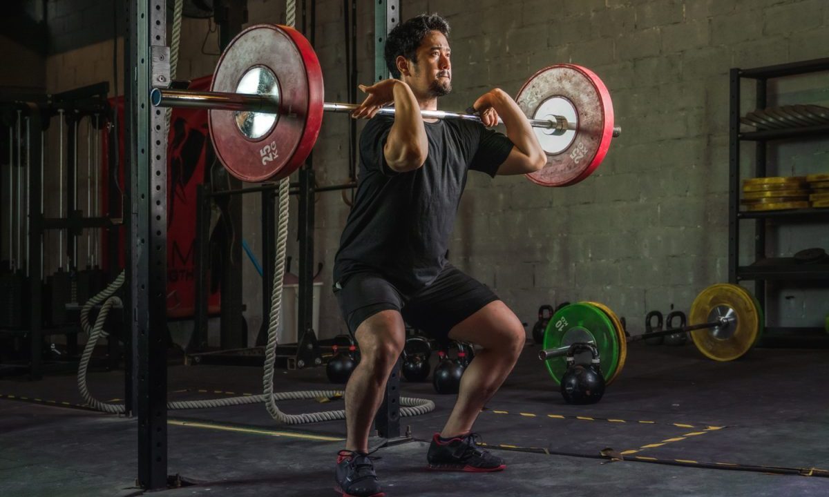 A man doing a front squat with a barbell.