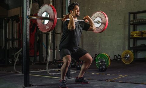 A man doing a front squat with a barbell.